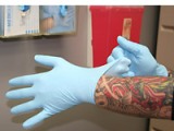 body artist with tattoos puts on protective gloves