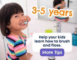 A smiling little girl brushing her teeth in front of the mirror